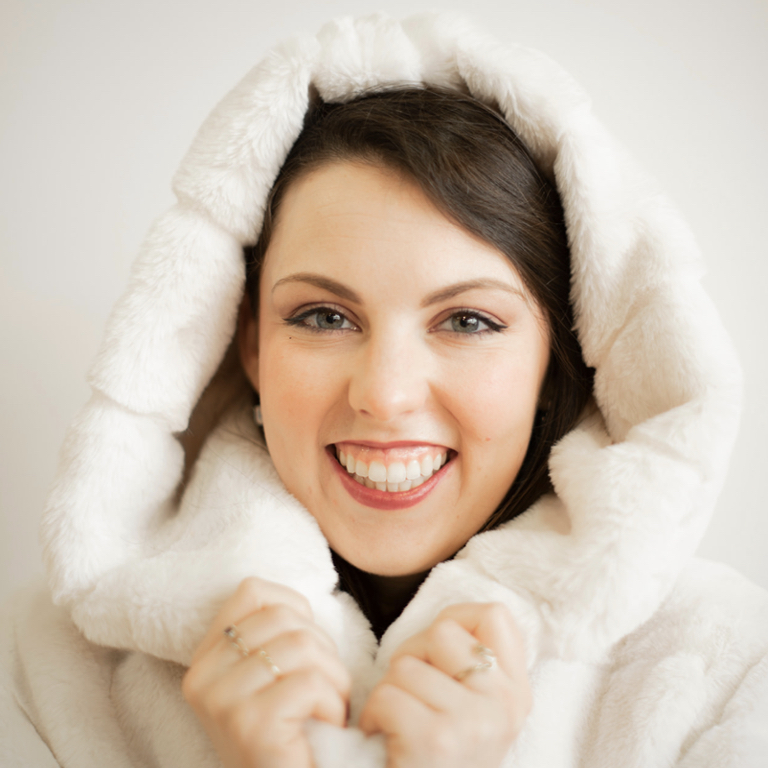 a person smiling with a fluffy white hooded coat