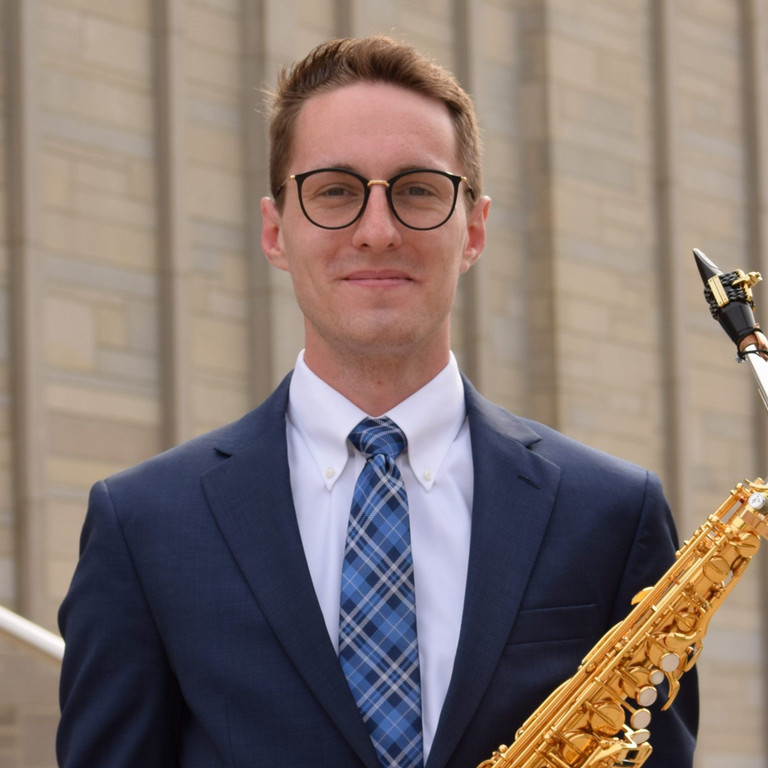 Man smiling holding a saxophone